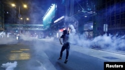 An anti-extradition bill protester throws a tear gas cartridge during clashes with police in Sham Shui Po in Hong Kong, Aug. 14, 2019.