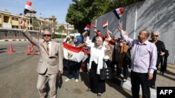 Les Egyptiens dansent avec des drapeaux égyptiens devant un bureau de vote au Caire, le 26 mars 2018.