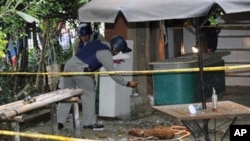 Police bomb personnel inspect the site where a book containing a bomb exploded while police were inspecting the package at the office of a moderate Islamic group in Jakarta, March 15, 2011