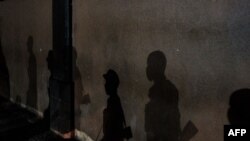 FILE - Shadows of Ugandan security personnel are seen in Kampala, Uganda, April 29, 2020. A Ugandan writer was reportedly arrested Friday for his work on an unpublished book that details his arrest and alleged torture in April by military personnel.