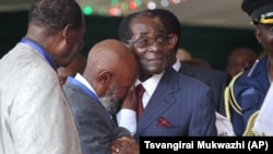 FILE An unidentified man who was in jail with Zimbabwean President Robert Mugabe during the liberation struggle, cries, as he greets him, during celebrations to mark his 92nd Birthday celebrations in Masvingo about 300 kilometres south of Harare, Saturday, Feb, 27, 2016. (AP Photo/Tsvangirayi Mukwazhi)