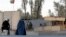Civilians wait as Afghan security forces guard at the main gate of Kandahar civilian airport during a clash between Taliban fighters and Afghan forces, in Kandahar, Afghanistan, Dec. 9, 2015. 