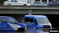 Seorang pengemudi berusaha memindahkan mobilnya melewati jalanan yang digenangi banjir akibat badai el-Nino di San Diego, California (6/1).