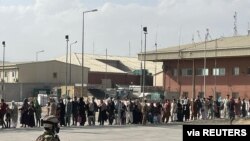 Afganos que esperan salir del país hacen cola antes de abordar uno de los últimos aviones militares italianos C130J durante la evacuación en el aeropuerto de Kabul, Afganistán, el 27 de agosto de 2021.