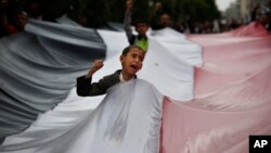 Mvulana akipiga kelele akiwa amejipenyeza kwenye bendera ya waasi wa Kihouthi wakati wa maandamano dhidi ya shambulizi la anga lililofanywa na Saudia Arabia nchini Yemen.