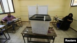 Election officials aElection officials wait for voters inside a polling station on the second day of voting in the Egyptian election in Cairo, May 27, 2014.