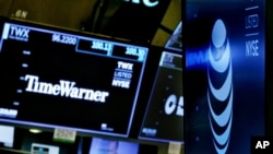 FILE - In this June 13, 2018, file photo, the logos for Time Warner and AT&T appear above alternate trading posts on the floor of the New York Stock Exchange.