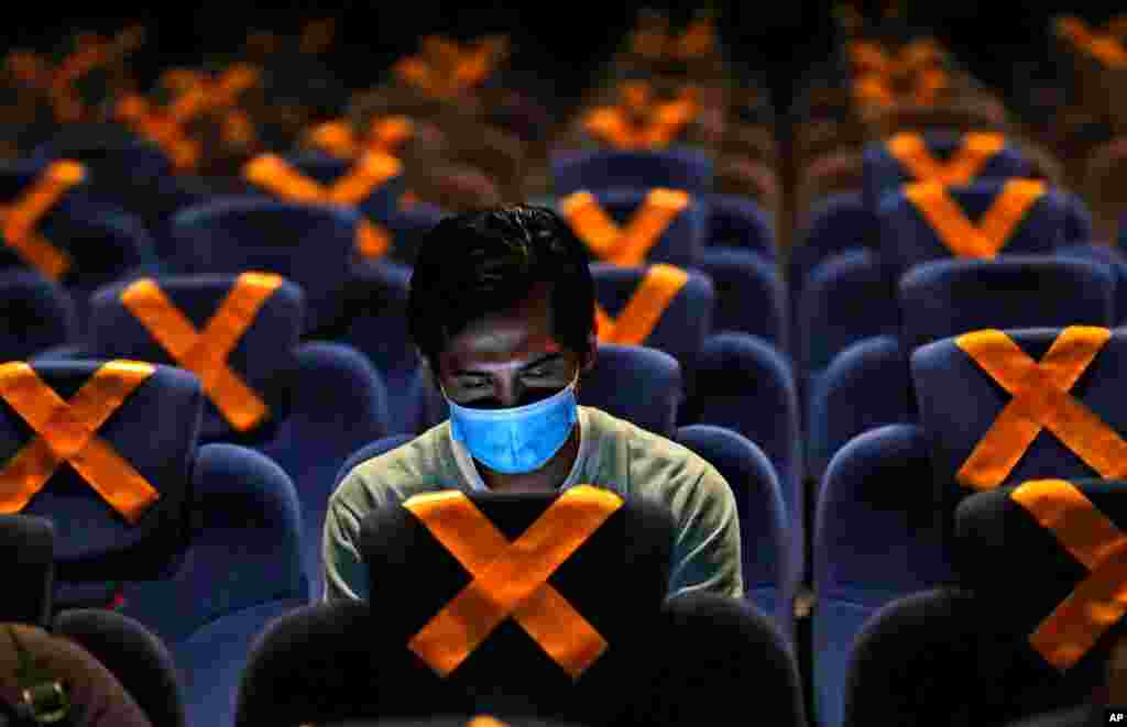 A man checks his mobile phone as he sits amid physical distancing markers prior to the start of a movie at CGV Cinemas theater in Jakarta, Indonesia. (AP)