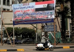 A man drives his motorcycle in front of a banner reading in Arabic, "Participation in constitutional amendments is a national duty", in Cairo, Egypt April 3, 2019.