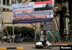 A man drives his motorcycle in front of a banner reading in Arabic, "Participation in constitutional amendments is a national duty", in Cairo, Egypt April 3, 2019.