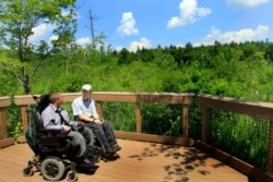 FILE - Two men in wheeelchairs enjoy the view at an overlook at Crotched Mountain Rehabilitation Center in Greenfield, New Hampshire, June 16 2011. The center offers trails designed to be easily accessible for people in wheelchairs.