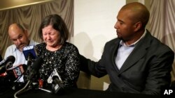 Former NFL player Dorsey Levens, right, extends a hand as Mary Ann Easterling, the widow of former NFL player Ray Easterling, reacts during a news conference, April 9, 2013, in Philadelphia, after a hearing to determine whether the NFL faces years of litigation over concussion-related brain injuries. 