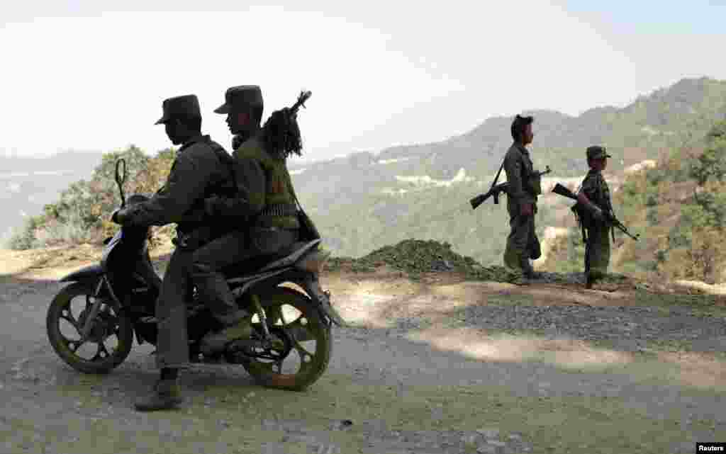 A 15-year-old soldier (R) stands next to other rebel soldiers of the Myanmar National Democratic Alliance Army (MNDAA) as they guard near a military base in Kokang region March 12, 2015. Fighting broke out last month between Myanmar&#39;s army and MNDAA, which groups remnants of the Communist Party of Burma, a powerful Chinese-backed guerrilla force that battled Myanmar&#39;s government before splintering in 1989. Picture taken March 12, 2015.