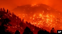 Seen in a long exposure photograph, embers light up hillsides as the Dixie Fire burns near Milford in Lassen County, Calif., on Tuesday, Aug. 17, 2021. 