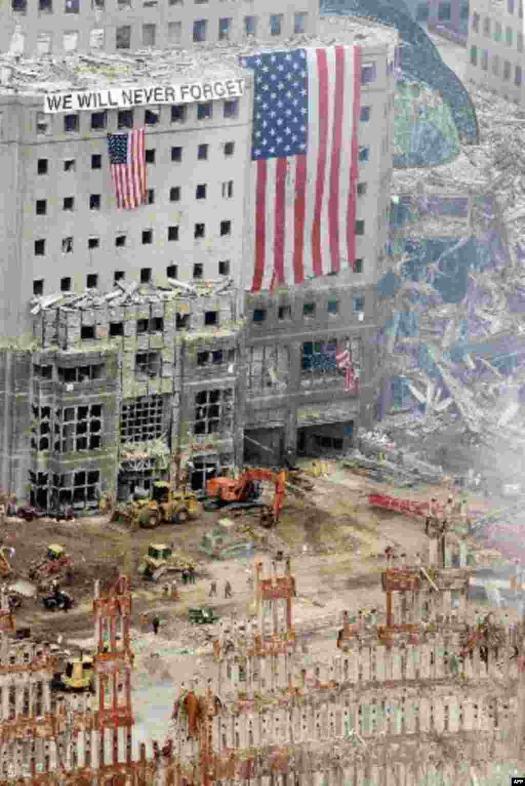 American flags and a sign reading "We Will Never Forget" hang from the heavily damaged American Express building on West Street across from the site of the terrorist attack on the World Trade Center in lower Manhattan Monday, Sept. 24, 2001. Part of the 