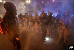 Federal officers advance on a group of demonstrators during a racial justice protest at the Mark O. Hatfield United States Courthouse July 25, 2020, in Portland, Ore.