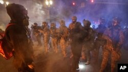 Federal officers advance on a group of demonstrators during a Black Lives Matter protest at the Mark O. Hatfield United States Courthouse, July 25, 2020, in Portland, Ore. 