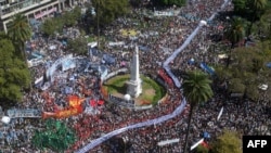 Aerial view of hundreds of people holding a large banner with portraits of people who disappeared during the military dictatorship (1976-1983) upon arrival at Plaza de Mayo Square to commemorate the 48th anniversary of the coup in Buenos Aires on March 24, 2023.