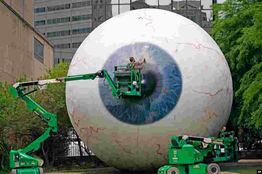Workers restore the fiberglass sculpture called "The Eye," created by artist Tony Tasset, in downtown Dallas, Texas. The 30-foot giant eye was vandalized.