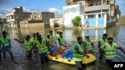 পাকিস্তানের করাচিতে ভারী বর্ষণের পর বন্যা প্লাবিত এলাকায় স্বেচ্ছাসেবকেরা খাদ্য বিতরণ করছেন, ২০শে অগাস্ট, ২০২১ ছবি, রিজওয়ান তাবাস্সুম-এএফপি 