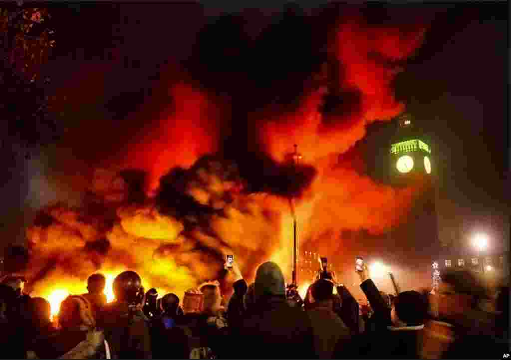 As a fire burned in Parliament Square, police officers with riot shields and batons pushed protesters back. (AP)