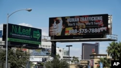 ARCHIVO - Un cartel muestra el número de teléfono de la Línea Directa Nacional contra la Trata de Personas, el 21 de septiembre de 2017, en Las Vegas, EEUU. El FBI en la ciudad se asoció con una empresa de vallas publicitarias en la lucha para detener la trata de personas.