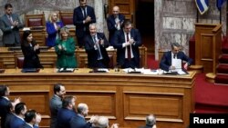 Greek Prime Minister Kyriakos Mitsotakis is applauded by members of his government during ahead of a vote on a bill which allows foreign private universities to set up branches in Greece, at the Greek parliament in Athens, March 8, 2024. 