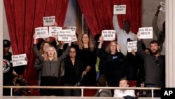 FILE - Protesters hold up signs in the House gallery opposing a bill pushed by the Tennessee Secretary of State that would impose new restrictions on groups that hold voter registration drives, in Nashville, Tenn., April 15, 2019. 