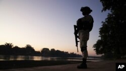 FILE - A Mexican National Guard stands on the bank of the Suchiate River, the natural border with Guatemala near Ciudad Hidalgo, Mexico. 
