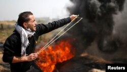 A Palestinian demonstrator hurls stones at Israeli troops during clashes at a protest demanding the right to return to their homeland, at the Israel-Gaza border east of Gaza City, April 6, 2018.