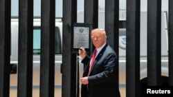 Presiden AS Donald Trump bersiap menandatangani plakat untuk memperingati pembangunan tembok perbatasan sepanjang 200 mil, saat meninjau tembok perbatasan AS-Meksiko di San Luis, Arizona, 23 Juni 2020.