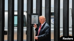 FILE - U.S. President Donald Trump prepares to autograph a plaque commemorating the construction of the 200th mile of border wall while visiting the wall on the U.S.-Mexico border in San Luis, Arizona, June 23, 2020.