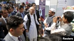 Afghan President Ashraf Ghani, using crutches after recent foot surgery, talks to participants at an exhibition of Afghanistan products during the Regional Economic Cooperation Conference of Afghanistan (RECCA) in Kabul, Afghanistan, Sept. 4, 2015.
