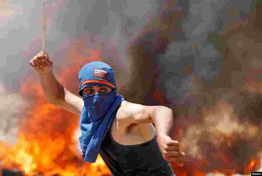 A Palestinian demonstrator uses a sling to hurl stones at Israeli troops during a protest against Jewish settlements and Israel's plan to annex parts of the occupied West Bank, near Ramallah.