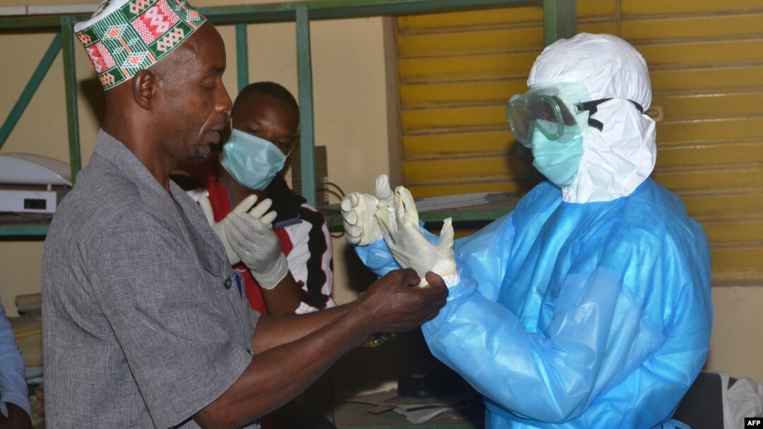 Para pekerja membuka baju pelindung dari virus Ebola setelah jam kerja mereka selesai di sebuah rumah sakit di Guinea (25/8/2014). 