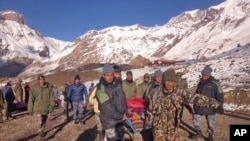 Para tentara Nepal mengangkat seorang korban salju longsor dengan tandu, sebelum diterbangkan dengan helikopter di area Thorong La, Nepal (15/10).