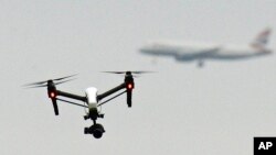 FILE - A drone flies in Hanworth Park in west London as a British Airways plane in the background prepares to land at Heathrow Airport, Feb. 25, 2017. Britain's aviation regulator said Oct. 14, 2024, that it would allow drones to inspect infrastructure.