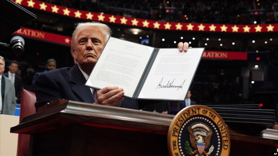 El presidente Donald Trump firma una orden ejecutiva mientras asiste a un desfile inaugural presidencial en el Capital One Arena, el 20 de enero de 2025, en Washington.