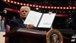 El presidente Donald Trump firma una orden ejecutiva mientras asiste a un desfile inaugural presidencial en el Capital One Arena, el 20 de enero de 2025, en Washington.