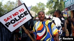 FILE - A protester holds a placard during an anti-police brutality protest, in Abuja, Nigeria, Oct. 20, 2021.