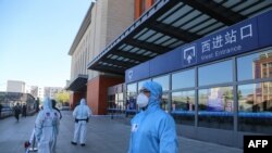 Agentes de policía vestidos con trajes protectores hacen guardia frente a la estación de trenes de la ciudad de Jilin, tras un brote de coronavirus local que ha alimentado los crecientes temores de una segunda ola de infecciones. Mayo 13 de 2020.