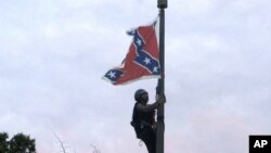 Bree Newsome dari Charlotte, North Carolina, memanjat tiang bendera untuk menurunkan bendera Konfederasi di monumen Konfederasi di Columbia, South Carolina (27/6). (AP/Bruce Smith)