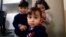 Syrian refugee Mohammad word al Jaddou, front, stands in front of his siblings twins Maria, right, and Hasan at their apartment in Dallas. 