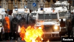A fire burns in front of the police on Springfield Road as protests continue in Belfast, Northern Ireland, April 8, 2021. 