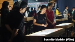 Penonton konser melihat-lihat pameran foto korban penculikan di Toba Tabo Cafe Jakarta, Sabtu, 6 April 2019. (Foto: Sasmito Madrim/VOA)