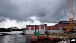 FILE - Rain clouds gather over a pumping station at Marconi Drive and lake Pontchartrain in New Orleans, Aug. 10, 2017.