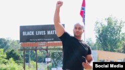 Kerwin Pittman, founder of Recidivism Reduction Educational Program Services, poses in front of the Black Lives Matter billboard set next to a Conferedate flag in a photo from his Facebook page. (Photo by Bee Ess)