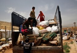 A Syrian family loads their belongings on a pickup, as they evacuate an informal refugee camp.