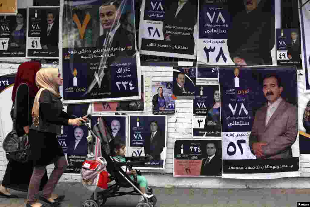 People walk past campaign posters for Iraq's parliamentary elections in Sulaimaniya, April 28, 2014. 