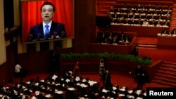 China's Premier Li Keqiang is seen on a screen delivering the government work report during the opening ceremony of the National People's Congress (NPC) at the Great Hall of the People in Beijing, March 5, 2014.